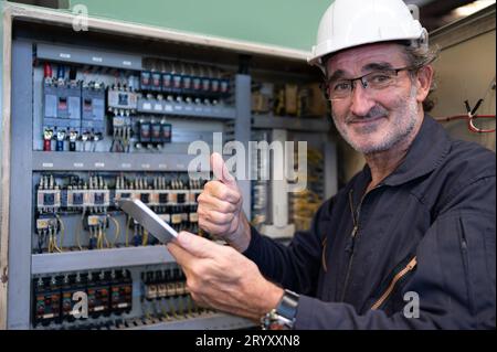 Senior engineer inspects the electrical system and repairs the mechanical system in the machine control cabinet. in order for th Stock Photo