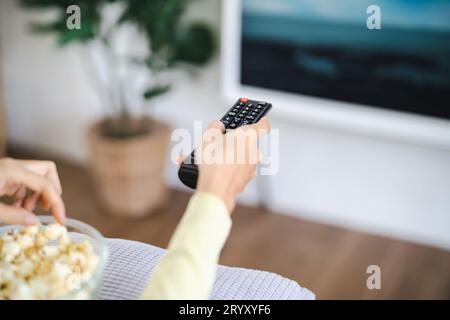 Asian woman Watching smart TV and using remote controller Hand holding television audio remote control at home with the remote c Stock Photo