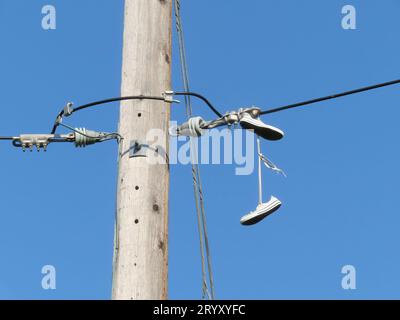 Sneakers Hanging from Power Lines. Concept: Secret Message, shoefiti or shoe tossing Stock Photo