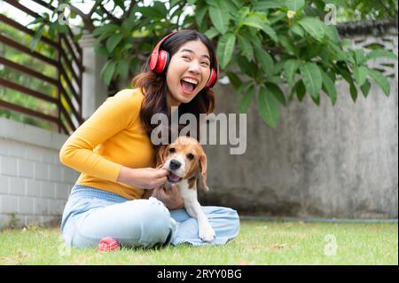 Young asian woman and beagle puppy relaxing on weekends in the front yard. Stock Photo