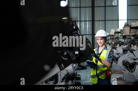 A female engineer installs a program on a robotics arm in a robot warehouse. And test the operation before sending the machine t Stock Photo