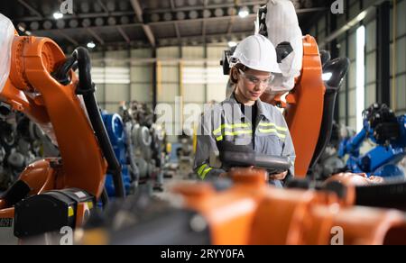 After installing a program on the robotic arm, a female engineer with a robotic arm controller performs a test run. Stock Photo