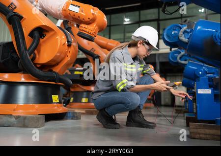 In the robots warehouse, A female engineer inspects the electrical system of every robotics arm, before delivering to the custom Stock Photo