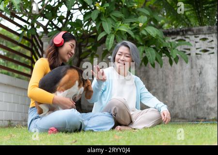 Family vacation, mother, daughter, and beagle puppy relaxing on weekends in the front yard. Stock Photo
