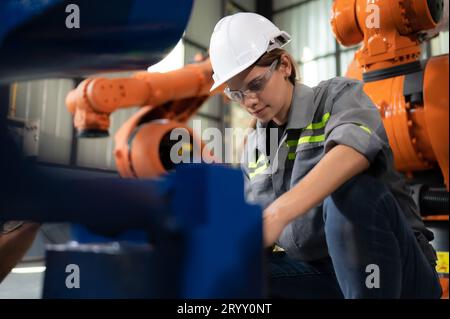 In the robots warehouse, A female engineer inspects the electrical system of every robotics arm, before delivering to the custom Stock Photo