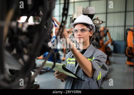 A female engineer checking documented items after installing a program on a robotic arm in a robotic warehouse and test the oper Stock Photo