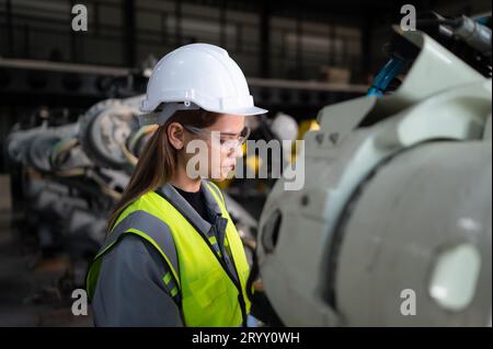 In the robots warehouse, Female engineer happily with updating software and calibrating a robotics arm. Stock Photo