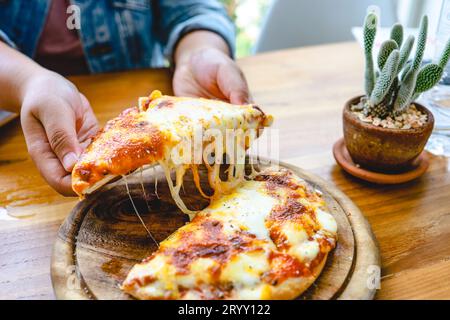 A slice of fresh hot Very cheesy vegetarian pizza mozzarella cheese. Italian Pizza Margherita in hand Stock Photo