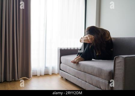 Sad woman thinking about problems sitting on a sofa upset girl feeling lonely and sad from bad relationship or Depressed woman d Stock Photo