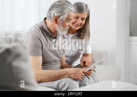 Senior couple solving crossword on sofa at home Stock Photo