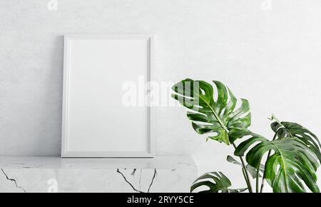 Empty photo frame mockup on white marble table with swiss cheese plant foreground on concrete background. Art and interior home Stock Photo