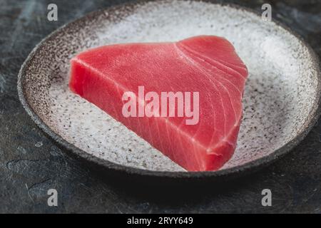 Raw fresh TUNA STEK on gray plate. Black background Stock Photo