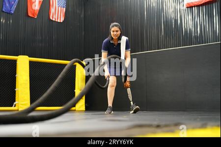 Young female with one prosthetic leg with doing arm and shoulder exercises with a rope to practice balancing with prosthetic leg Stock Photo