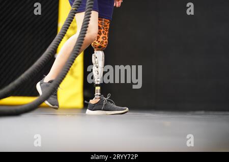 Young female with one prosthetic leg with doing arm and shoulder exercises with a rope to practice balancing with prosthetic leg Stock Photo
