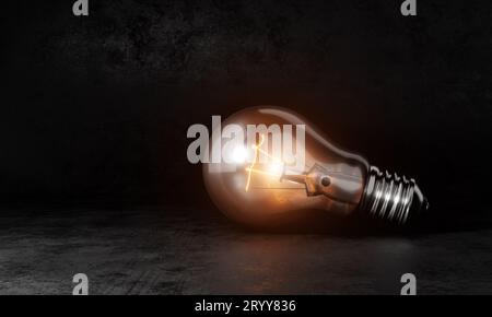 Light bulb with orange warm white light in dark room background and copy space. Conceptual and Creative invention symbol concept Stock Photo