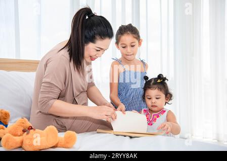 Asian mother teaching mixed raced girls daughter to reading books in their house. Quarantine in home concept. Happy family theme Stock Photo