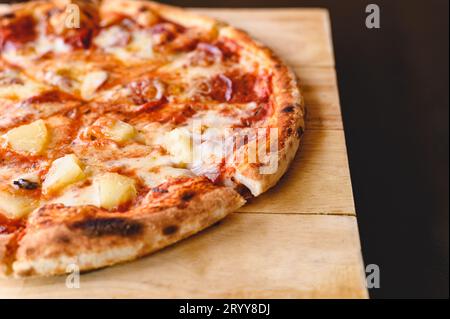 Tasty tradition Hawaiian and Salami pizza pie cooking ingredients bacon tomatoes on black table in original restaurant backgroun Stock Photo