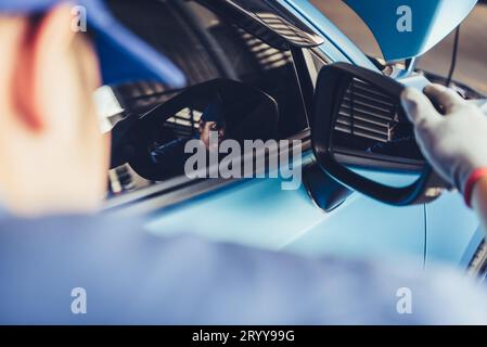 Mechanic car technician is looking at the rear view mirror for checking to maintenance vehicle by customer claim order in auto r Stock Photo
