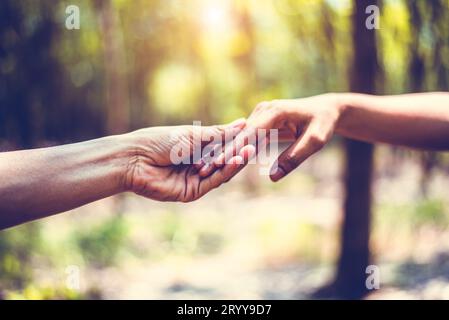 Closeup of helping hand of human during travel in forest. Hand in hand together. Two hands holding for support each others. Peop Stock Photo