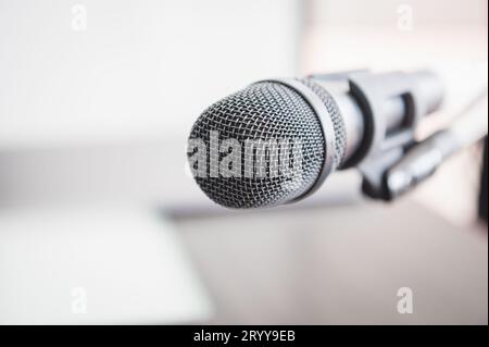 Closeup of microphone in lecture room background speech in seminar convention hall room. Mic speaker of teacher on podium in col Stock Photo