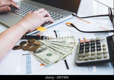 Close up of working woman hand using laptop computer on office desk with money report paper eyeglasses and calculator. Business Stock Photo