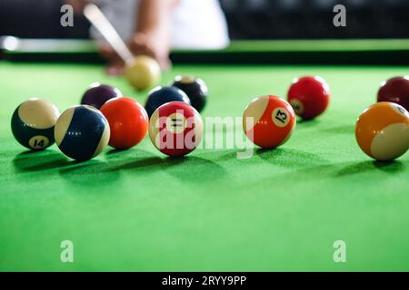 Man's hand and Cue arm playing snooker game or preparing aiming to shoot pool balls on a green billiard table. Colorful snooker Stock Photo