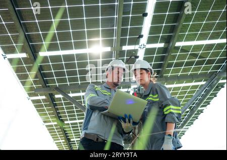 A team of electrical engineers is inspecting and maintaining solar panels at a solar panel site in the middle of a hundred acre Stock Photo