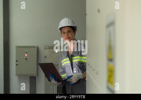 Young female engineer inspecting system of a large solar energy storage station in the middle of the field of solar cells on an Stock Photo