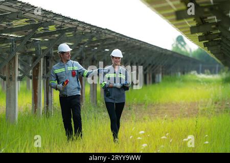 A team of electrical engineers is inspecting and maintaining solar panels at a solar panel site in the middle of a hundred acre Stock Photo
