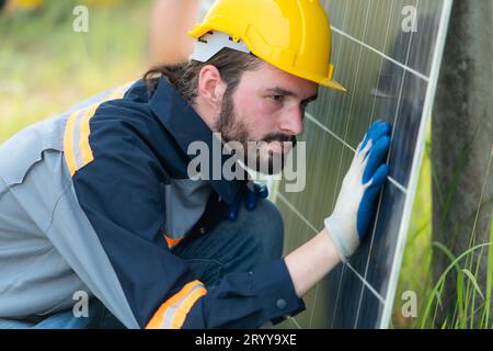 An electrical engineer is inspecting a solar cell that has been used for some time, installed on a field hundred acres of grass. Stock Photo