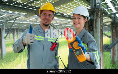 A team of electrical engineers is inspecting and maintaining solar panels at a solar panel site in the middle of a hundred acre Stock Photo