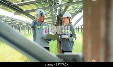 A team of electrical engineers is inspecting and maintaining solar panels at a solar panel site in the middle of a hundred acre Stock Photo
