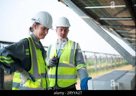 A team of electrical engineers is inspecting and maintaining solar panels at a solar panel site in the middle of a hundred acre Stock Photo