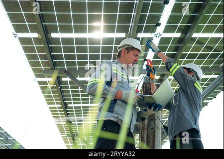 A team of electrical engineers is inspecting and maintaining solar panels at a solar panel site in the middle of a hundred acre Stock Photo