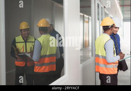 The warehouse manager advises the two employees on how to organize the shelves in a vast warehouse. Stock Photo