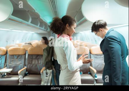 Flight attendant greet passengers as they enter the aircraft to locate a seat in the cabin. Stock Photo