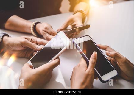 Group of young hipsters holding mobile phones in hands at office. Friends having fun together with smartphone. Technology and co Stock Photo