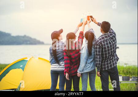Back view of friendship clinking drinking bottle glass for celebrating in private party with mountain and lake view background. Stock Photo