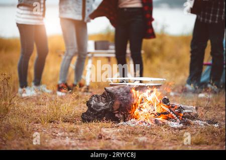 Closeup of campfire with friendship dancing to beat of the music for celebrating in party with mountain meadow and lake view bac Stock Photo
