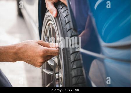 Closeup male automotive technician removing tire valve nitrogen cap for tire inflation service at garage or gas station. Car ann Stock Photo