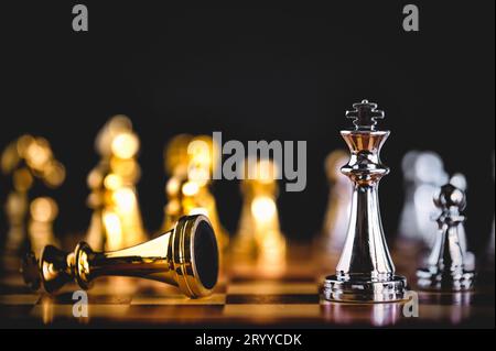 Closeup king chess piece defeated enemy or trade competitor by checkmate at end of chessboard game. Businessman moving chess to Stock Photo