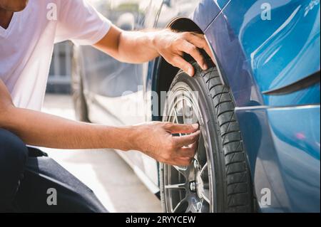 Closeup male automotive technician removing tire valve nitrogen cap for tire inflation service at garage or gas station. Car ann Stock Photo