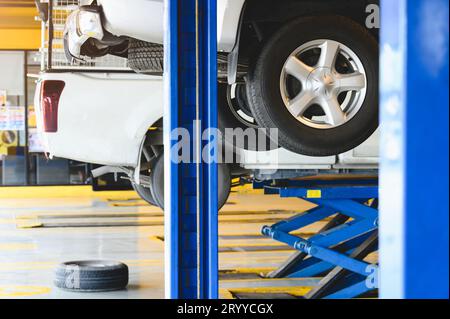 Pickup car raised on car lift in auto service garage center for tire change. Automotive car repairing and maintenance concept. Stock Photo