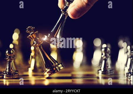 Closeup king chess piece defeated enemy or trade competitor by checkmate at end of chessboard game. Businessman moving chess to Stock Photo