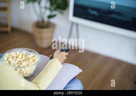 Asian woman Watching smart TV and using remote controller Hand holding television audio remote control at home with the remote c Stock Photo