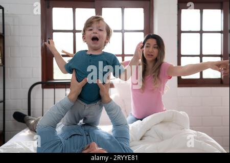 Little boy flying with dad using his legs to help him fly high off the floor of his bed in the bedroom. Stock Photo