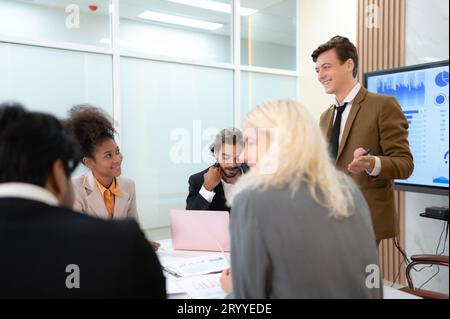 In the meeting room of an international business corporation, a diverse group of young entrepreneurs are enthusiastically taking Stock Photo