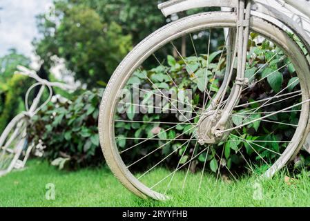 White bicycle in garden background. Vintage and nature concept. Close up and bike handle. Stock Photo