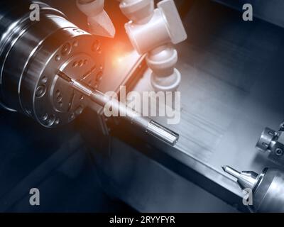 CNC lathe turning machine with shaft production. Industrial and Technology concept. Automotive and Material theme. Blue tone wit Stock Photo