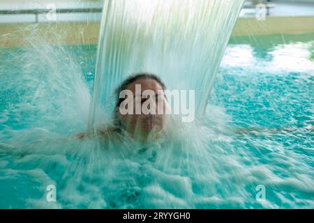Woman Face Relax in a Hydromassage Pool with Falling Water in Long Exposure in Switzerland Stock Photo
